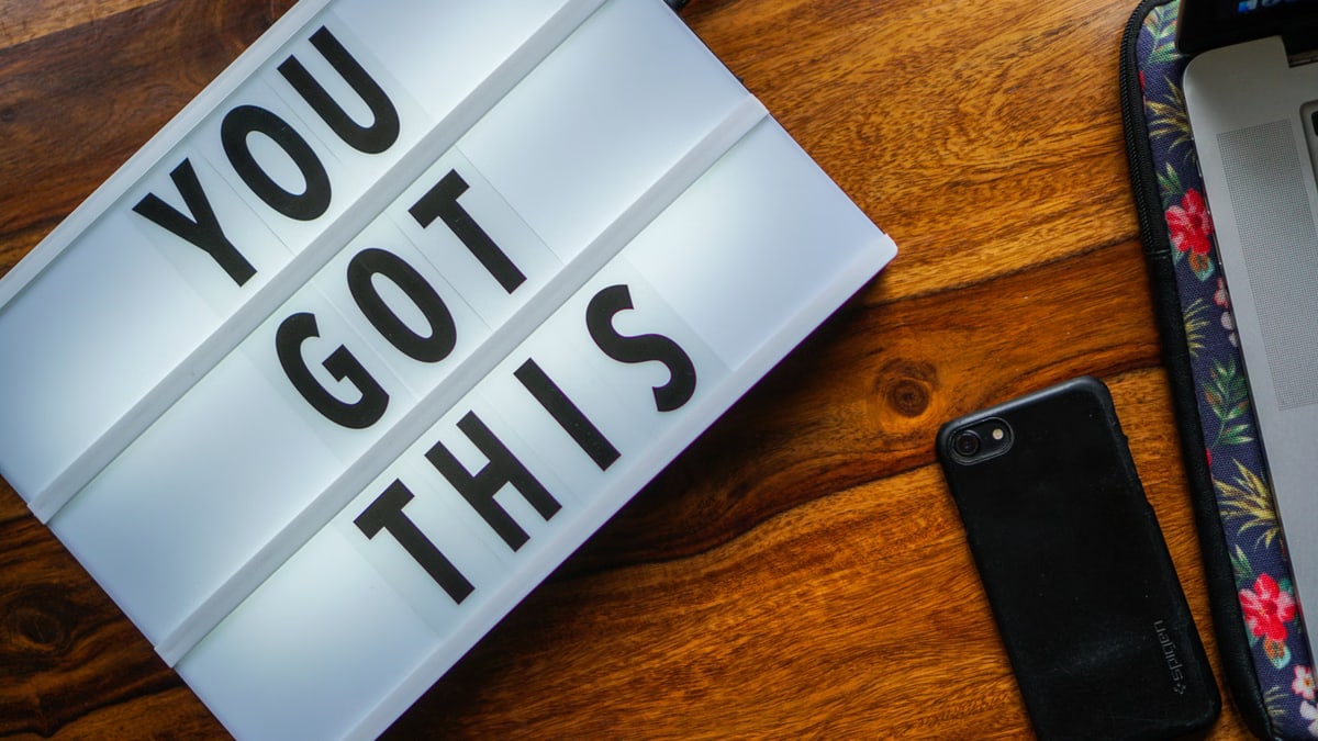 Motivational quote 'You Got This' on a lightbox, smartphone on a wooden table, cozy workspace vibe.